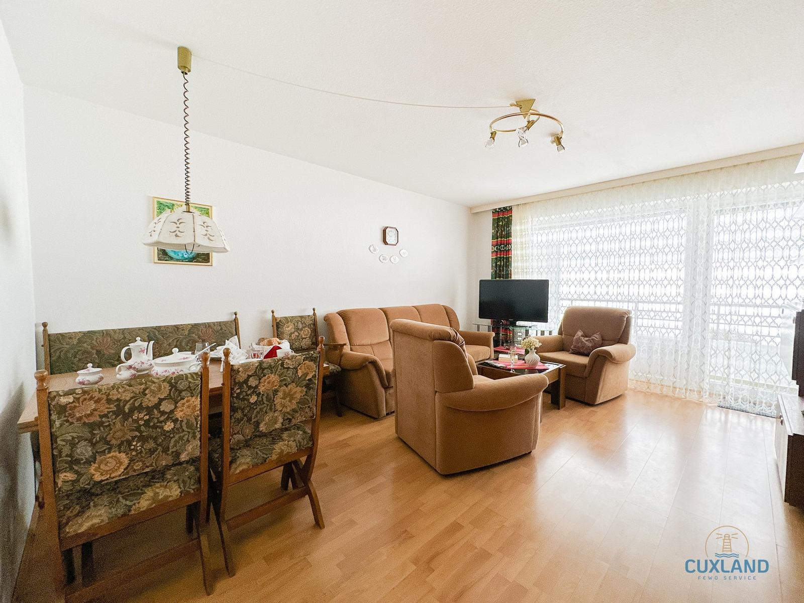 Wohn- und Essbereich mit Sofa, Sesseln und Esstisch.