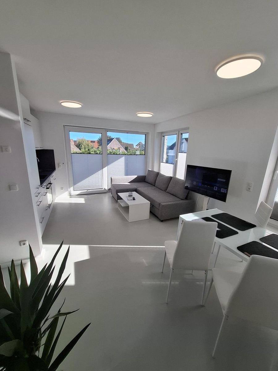 Wohn- und Essbereich mit Sofa, TV und großem Fenster. Moderne Einrichtung.