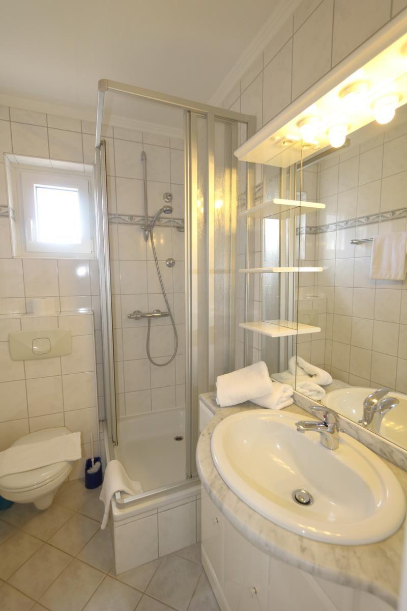 Badezimmer mit Dusche, Waschbecken und Toilette.