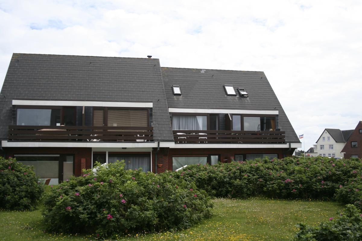 Zweistöckiges Haus mit Balkonen und begrüntem Vorgarten