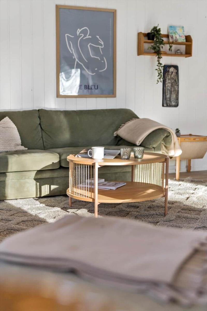 Ein Wohnzimmer mit grünem Sofa, Holztisch und Wandbild.