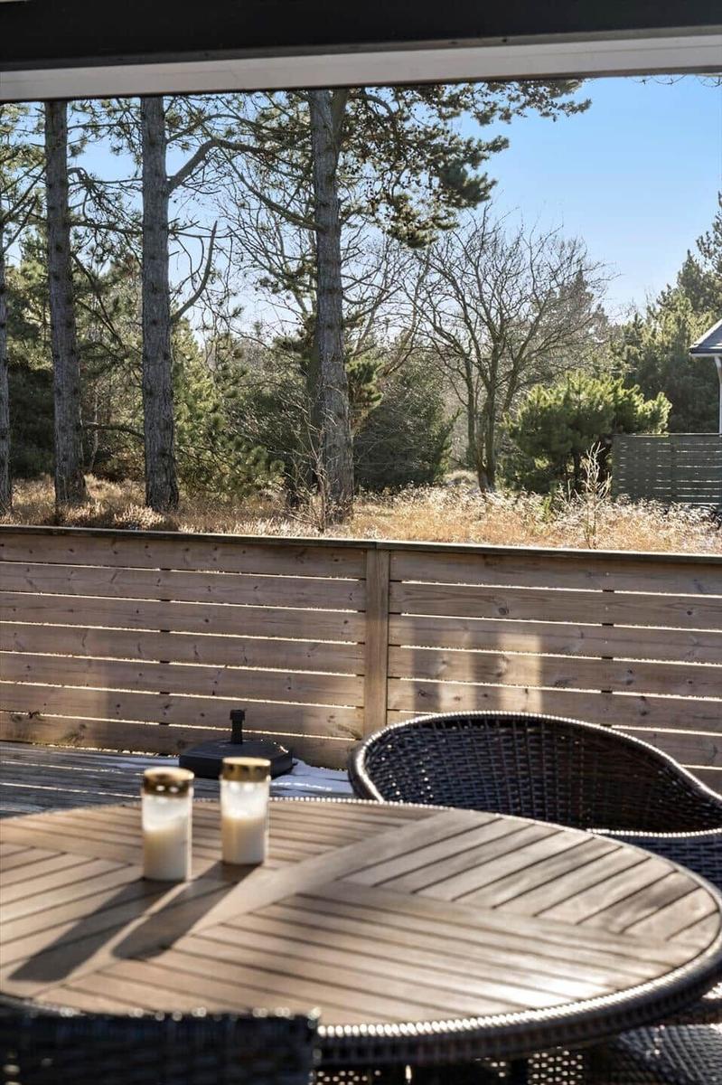 Terrasse mit Tisch, Stühlen und Blick auf Wald.