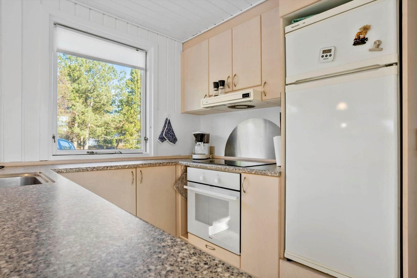 Küche mit Kühlschrank, Herd und Fenster zum Garten