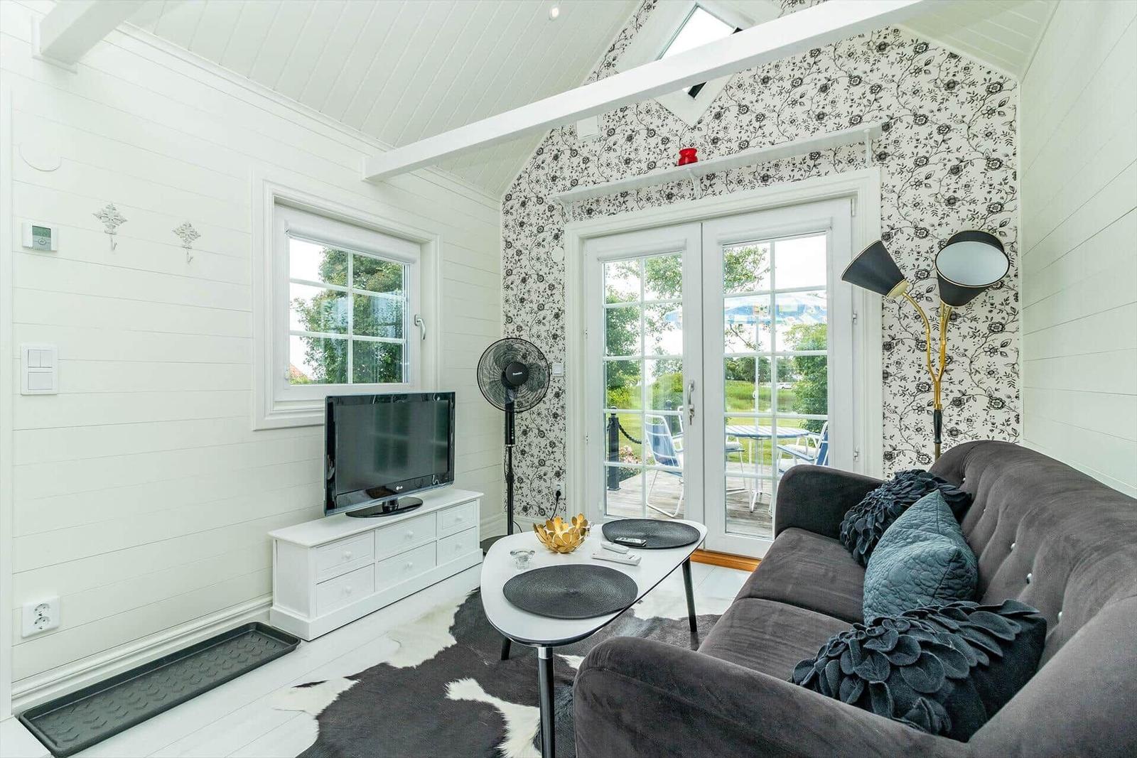 Wohnzimmer mit Sofa, Fernseher und Terrassentür.