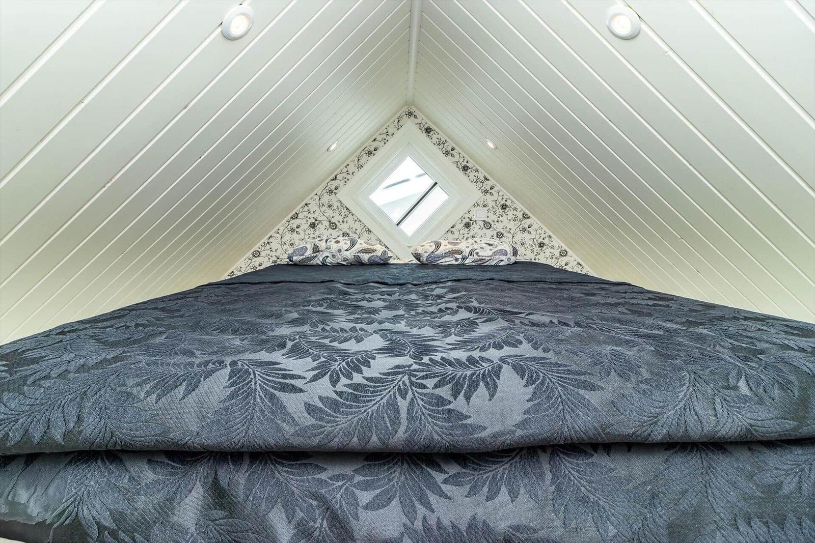 Schlafzimmer mit Dachschrägen, Dachfenster und gemusterter Bettwäsche.