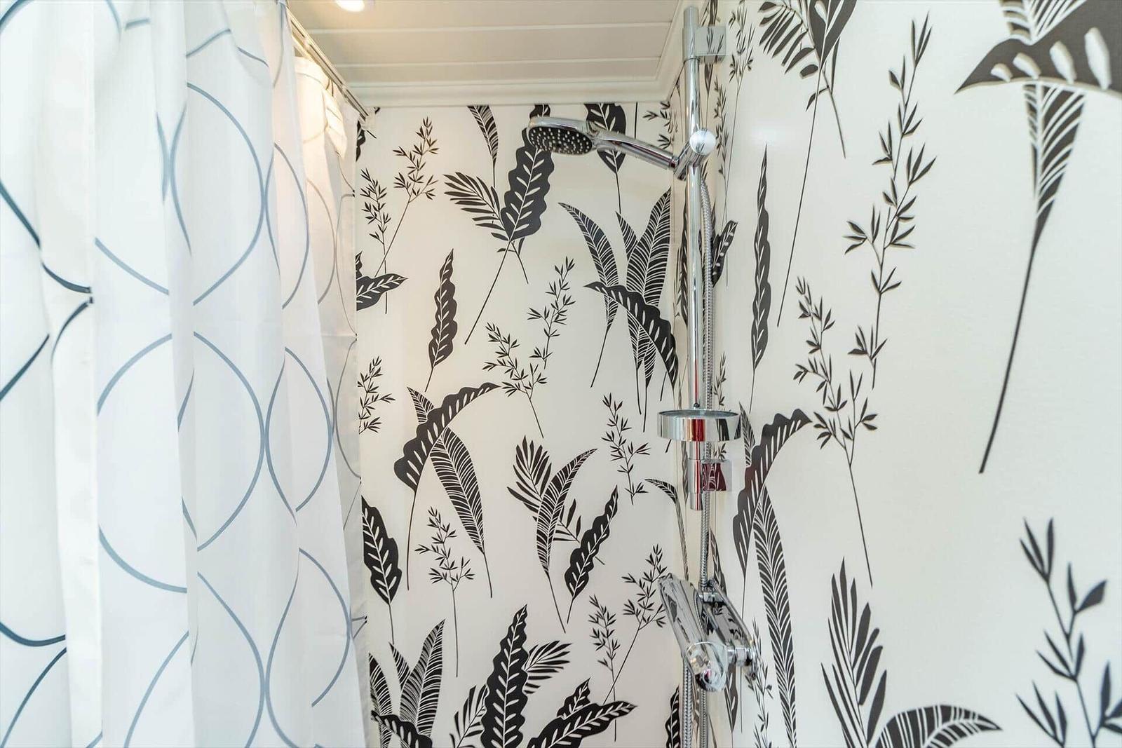 Dusche mit floraler Wandtapete und Duschvorhang.