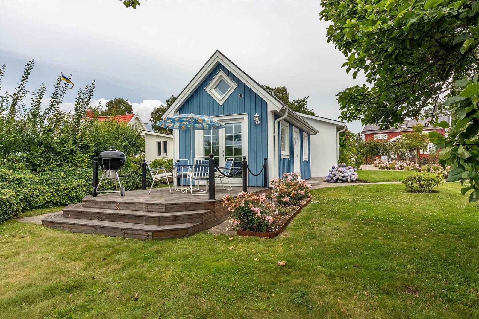 Blau-weißes Ferienhaus mit Terrasse, Grill und Garten.