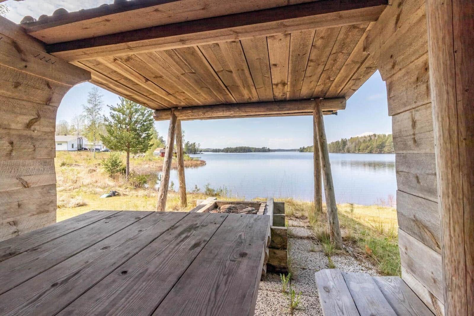Holzterrasse mit Tisch und Sitzgelegenheit am See.