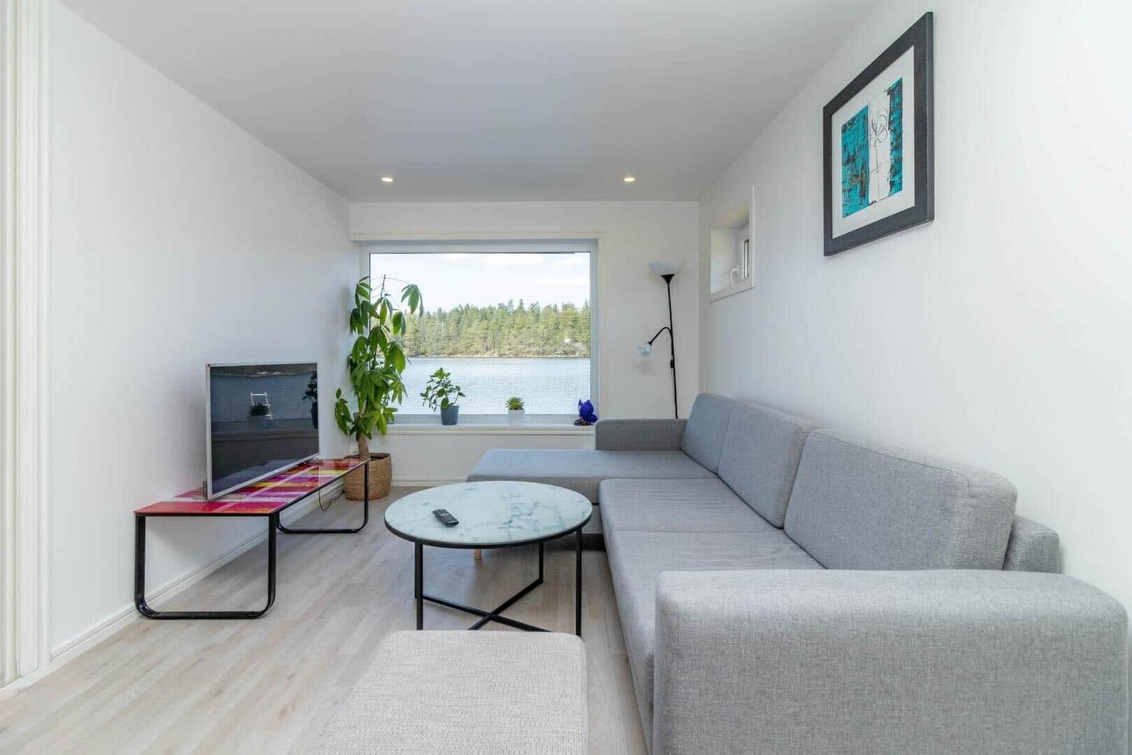 Wohnzimmer mit Sofa, Fernseher und Blick auf Wasser
