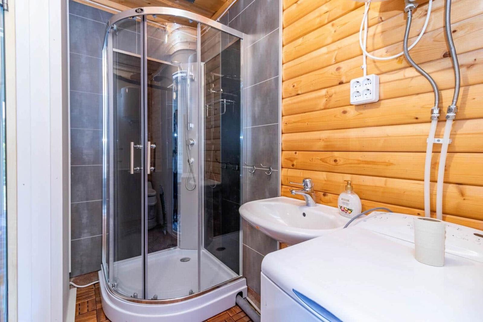 Badezimmer mit Dusche, Waschbecken und Waschmaschine.