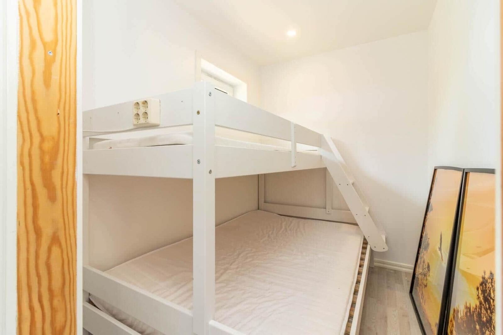 Zimmer mit Doppelstockbett, weiß lackiert, mit Matratzen und Leiter.