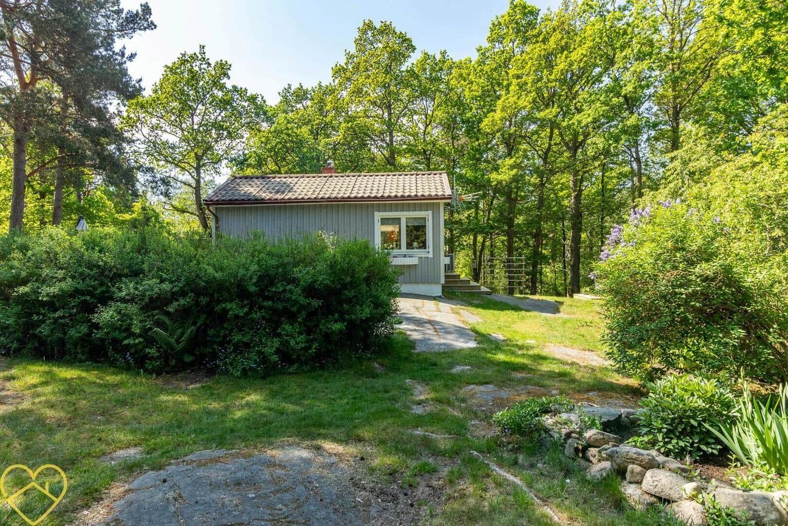 Ein kleines Haus mit Garten und Bäumen im Hintergrund.