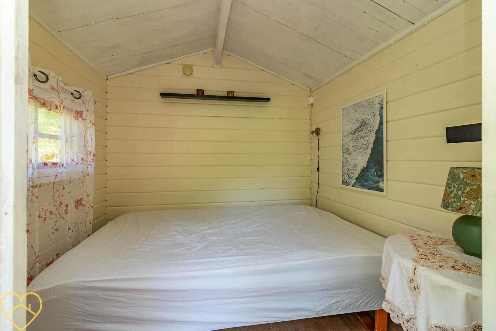 Schlafzimmer mit Bett, Fenster und Wandbild.