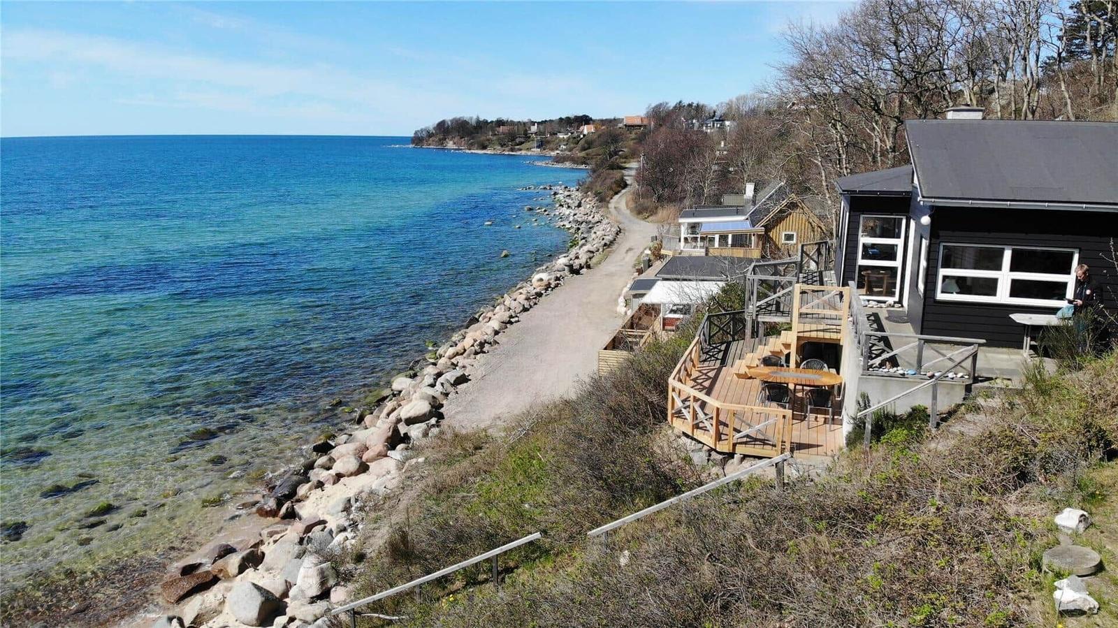 Black house with terrace along coastal path. View of the sea and rock breakwater.