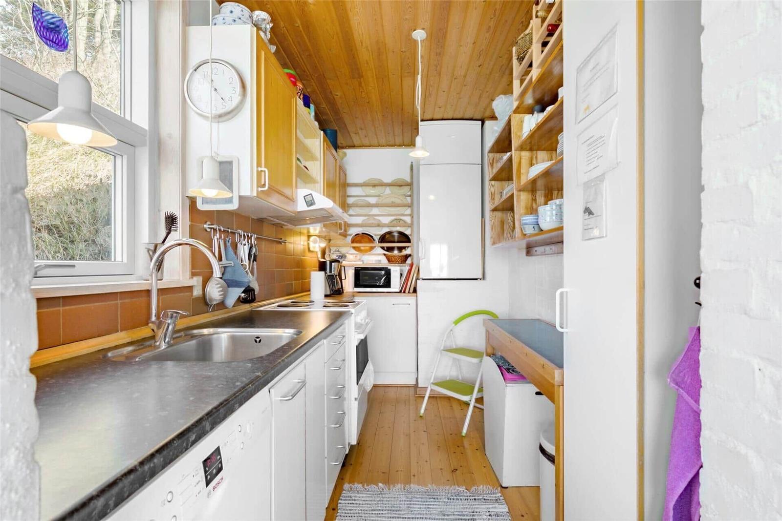 Kitchen with worktop, sink and appliances. Wooden ceiling and floor.
