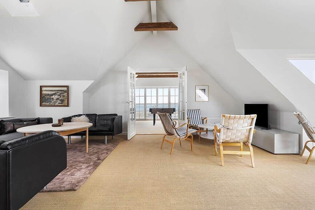 Living area with sofa, chairs, and TV under high ceiling
