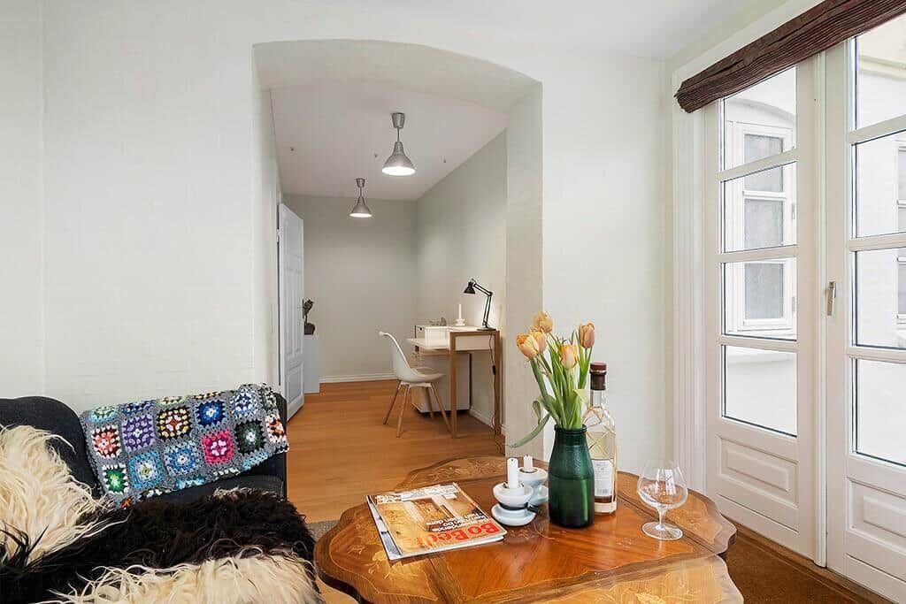 Living room with sofa, table, and view into hallway with desk.