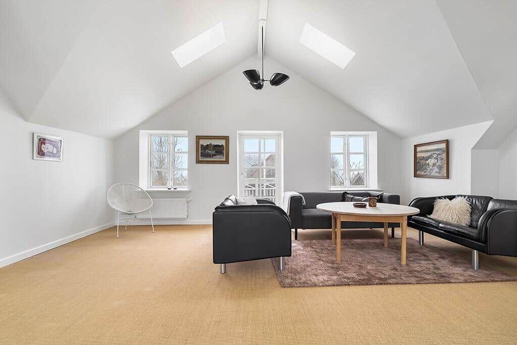 Living room with black sofa, round table, and sloped ceiling.