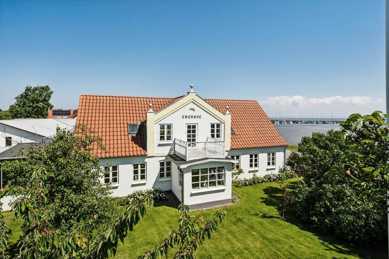 White house with red roof, balcony, and view of water
