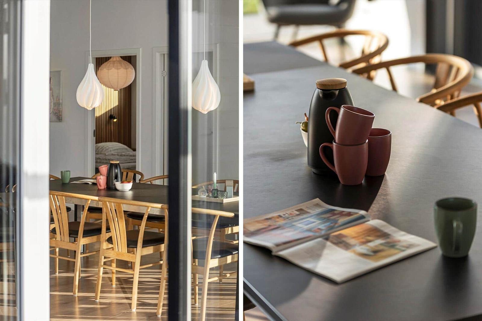 Dining table with chairs, mugs, and newspaper. Hanging lamps and view into bedroom.