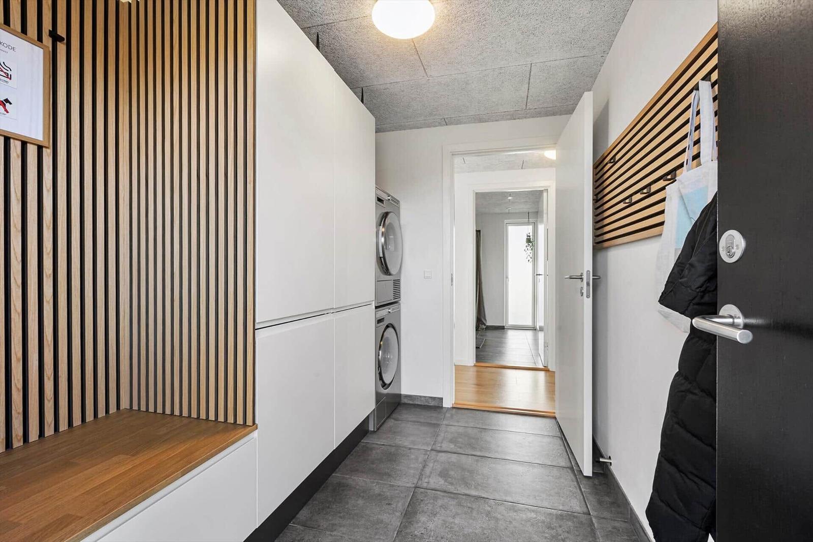 Hallway with washing machine, wooden wall, and coat rack