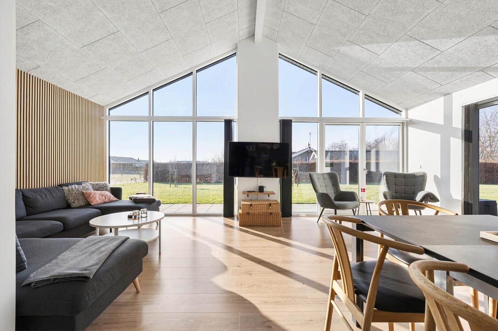 Large living room with glass front, sofa, dining table, and TV.