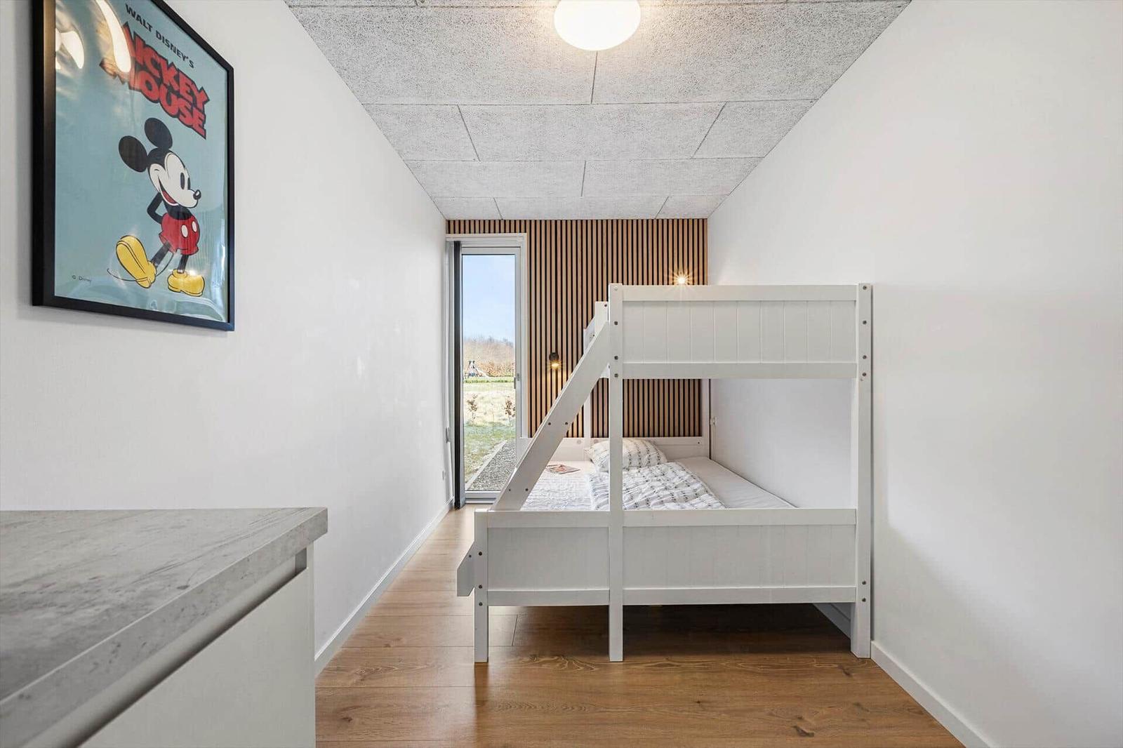 Bedroom with bunk bed and window to outdoor terrace.