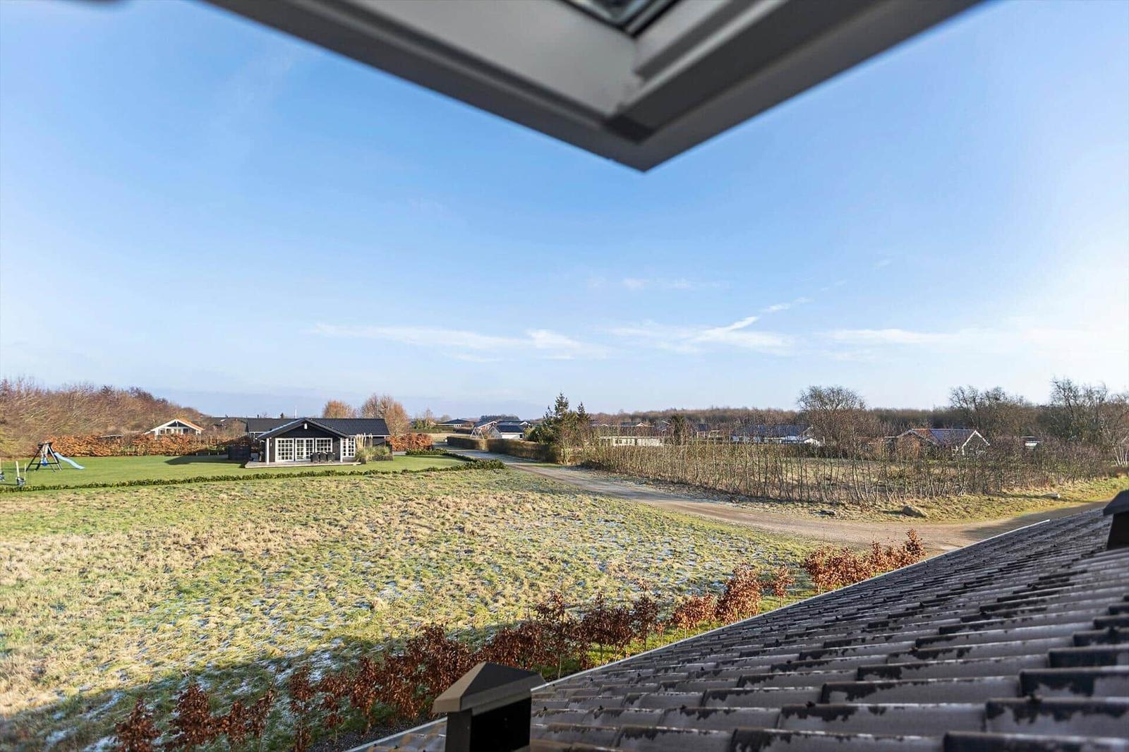 Wide view of green field and holiday homes under clear sky.