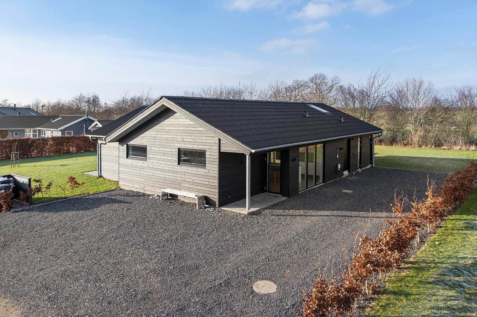 Modern villa with wooden facade and large garden. Garage and terrace are available.