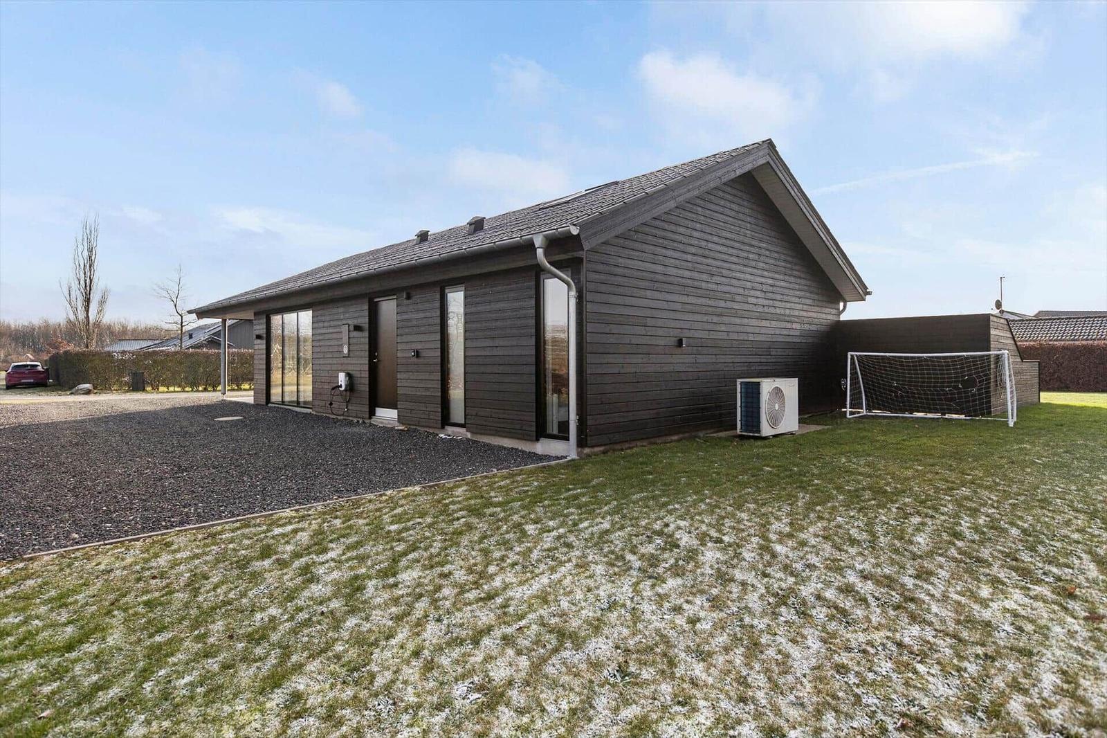 Modern wooden house with garden and soccer goal. Snow covers the lawn.