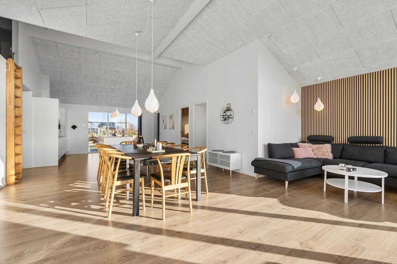 Large living and dining area with wooden floor and wood panel. Dining table with chairs and sofa.