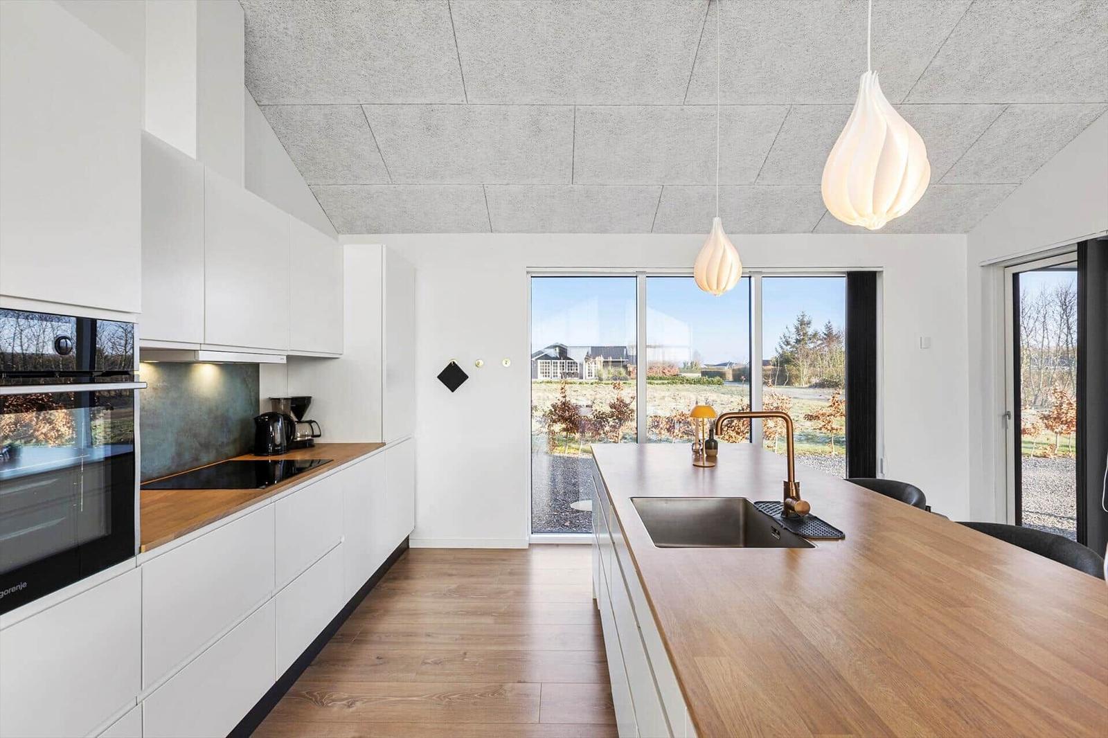 Modern kitchen with wooden countertop and large window view.