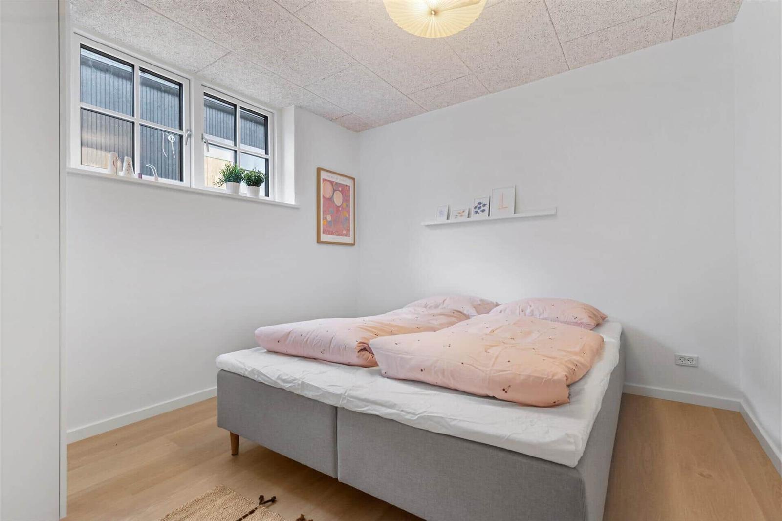 Schlafzimmer mit Bett, Fenster und Deckenleuchte.