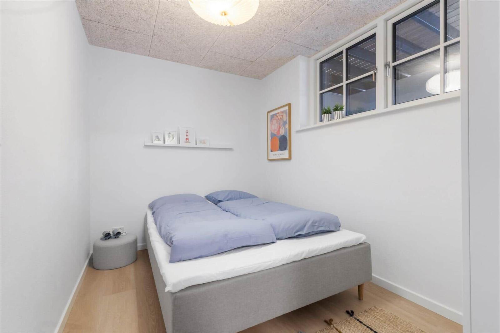 Schlafzimmer mit Bett, Fenster und Wandbild.