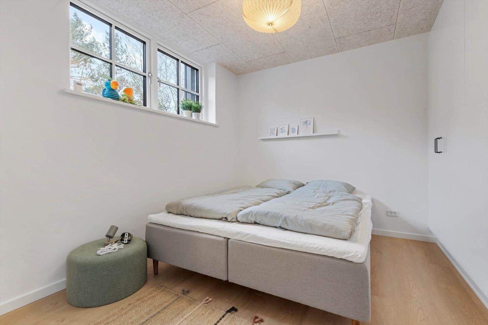Schlafzimmer mit Doppelbett, Fenster und Holzboden.