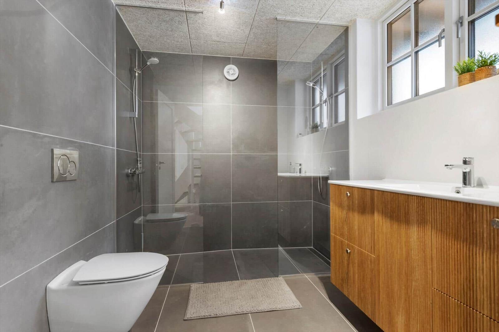 Badezimmer mit Dusche, Toilette und Waschbecken mit Holzfront