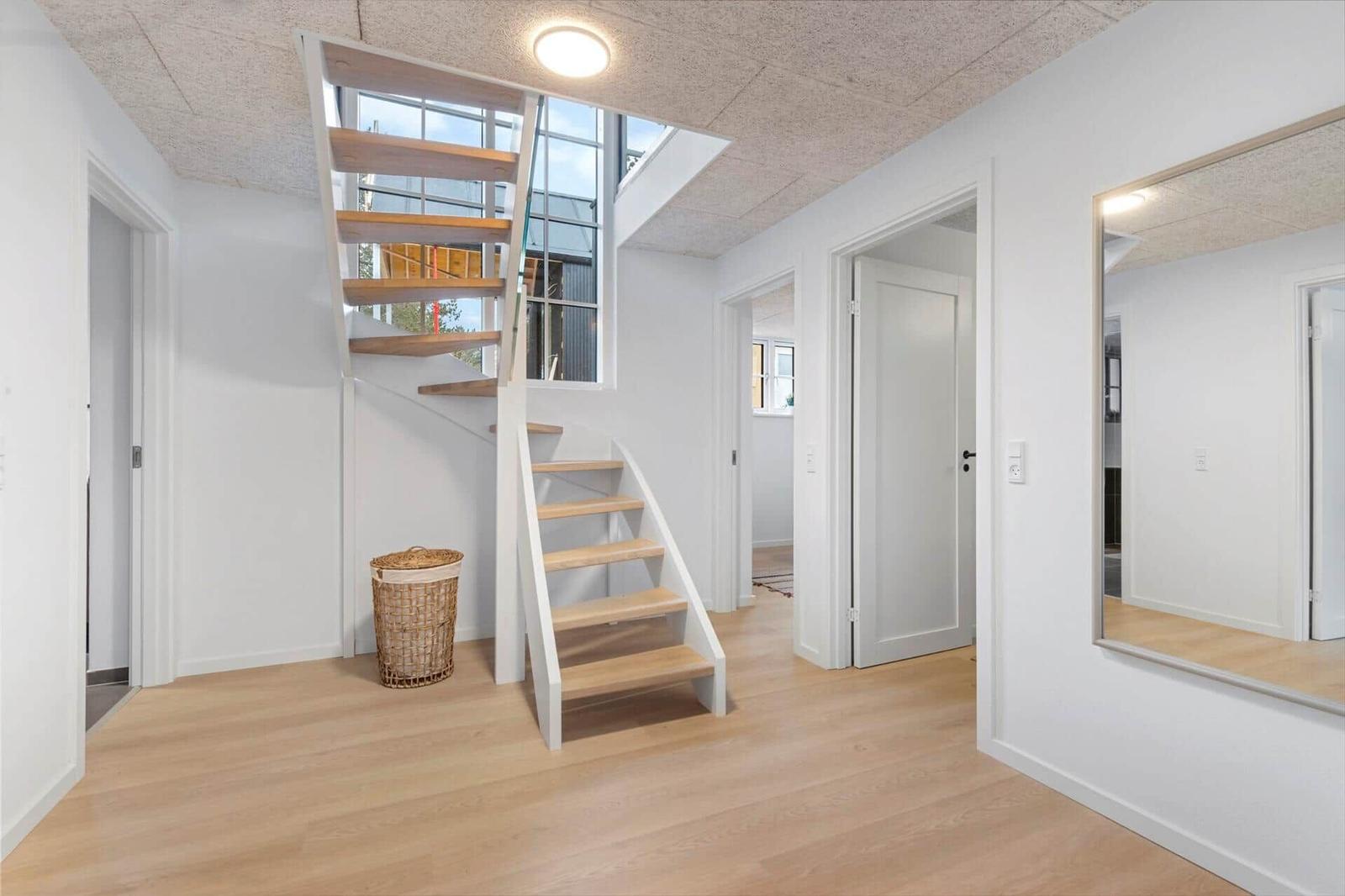 Haus mit Treppe, Spiegel und Eingangsbereich mit hellen Wänden und Holzboden.