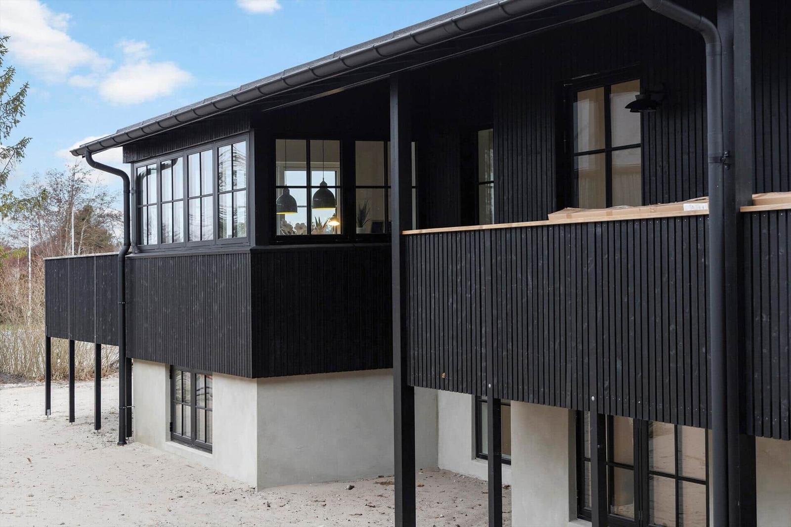 Moderne Ferienwohnung mit schwarzem Holzverkleidung und großzügigen Fenstern.