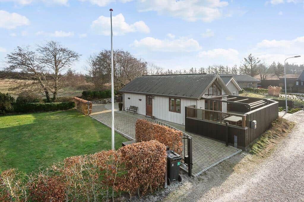 Moderne Villa mit Terrasse, Rasen und Gartenzaun. Blick auf den Hof und die Umgebung.