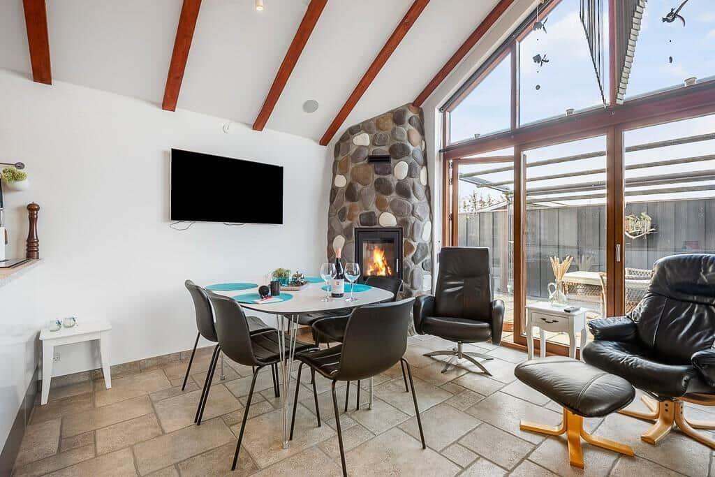 Essbereich mit Esstisch, Stühlen und Kamin. Große Glasfront mit Sitzgelegenheiten.
