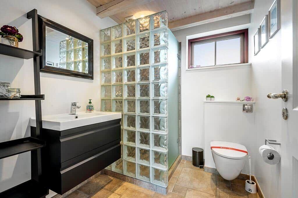 Badezimmer mit Glasblockwand, Waschbecken und Toilette.