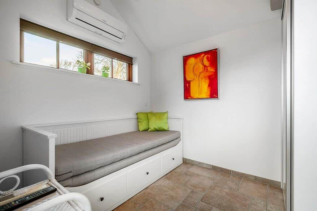 Schlafzimmer mit Fenster, Bett und Wandbild.