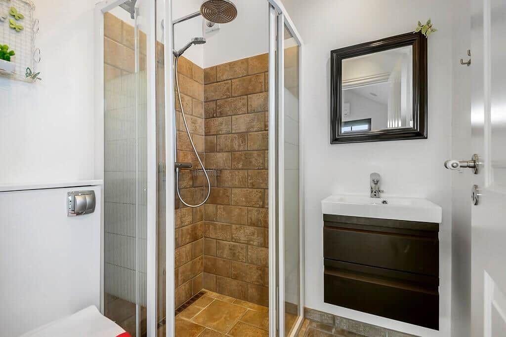 Dusche mit Glaswand, Waschbecken und Spiegel im Badezimmer