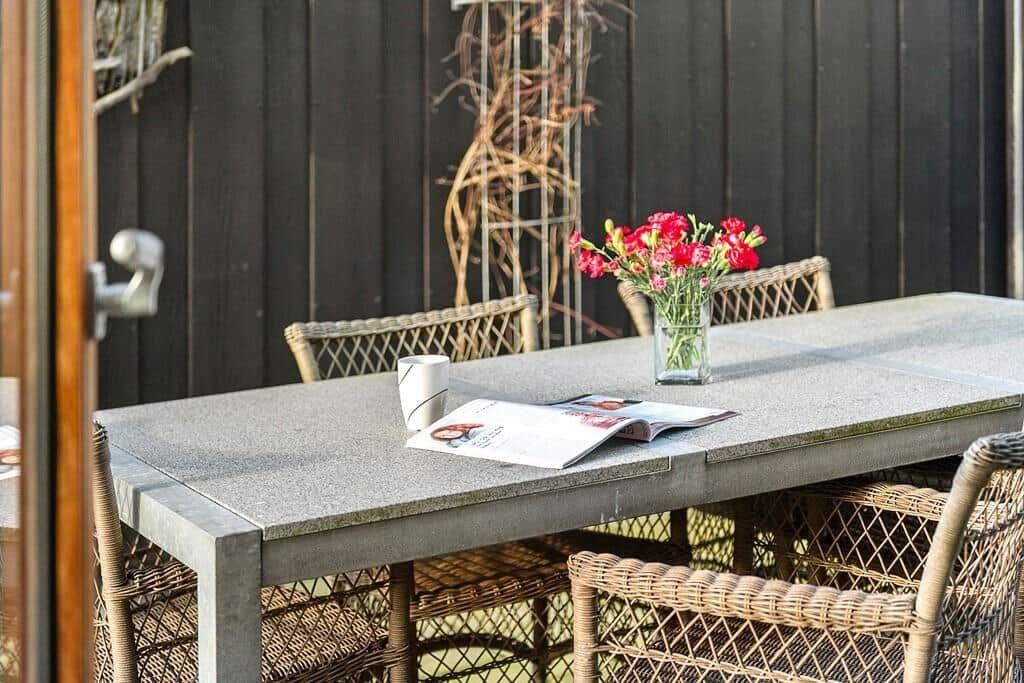 Terrassentisch mit Stühlen, Blumen und Zeitschrift
