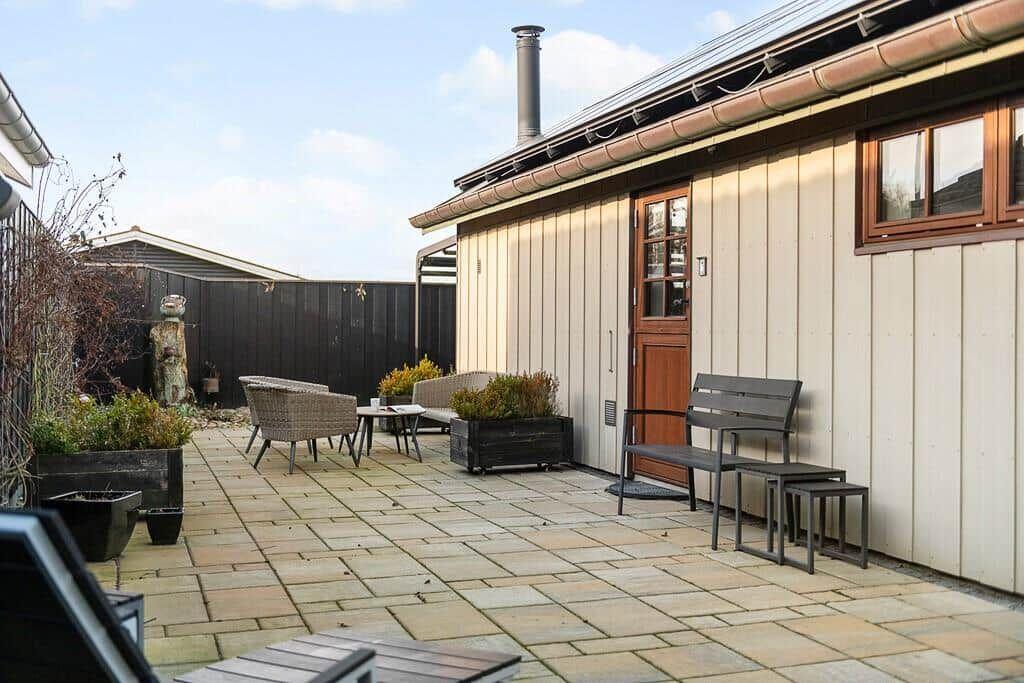 Terrasse mit Sitzgelegenheiten und Pflanzen vor einem Holzhaus.