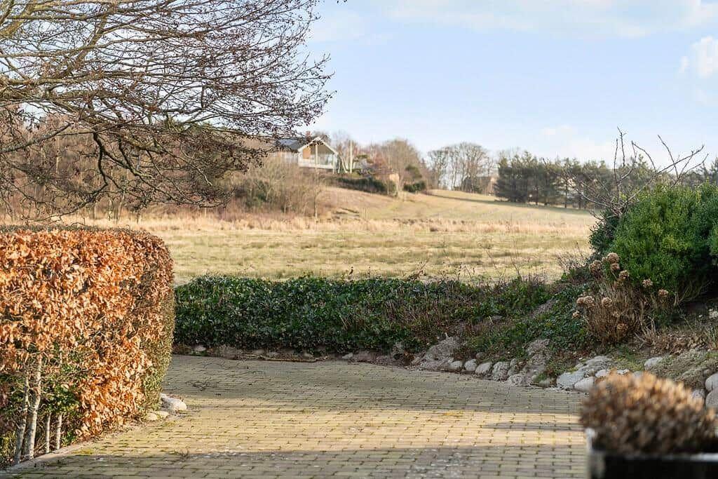 Pflasterweg führt durch Garten zu Ferienhaus im Hintergrund.