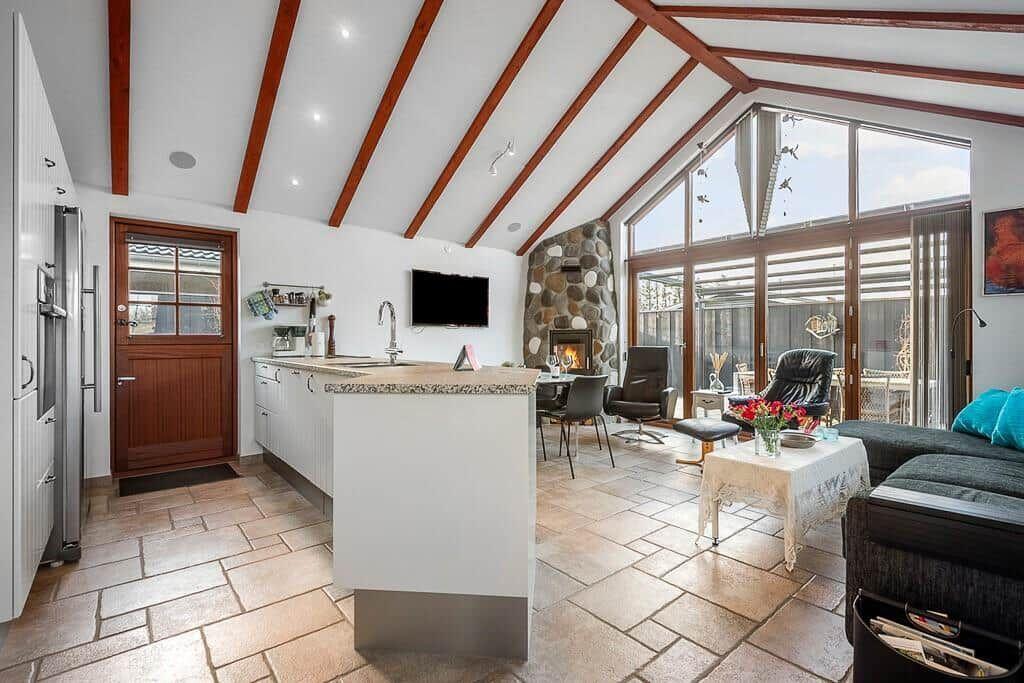 Küche mit Insel, Wohnbereich mit Kamin und großem Fensterbereich.