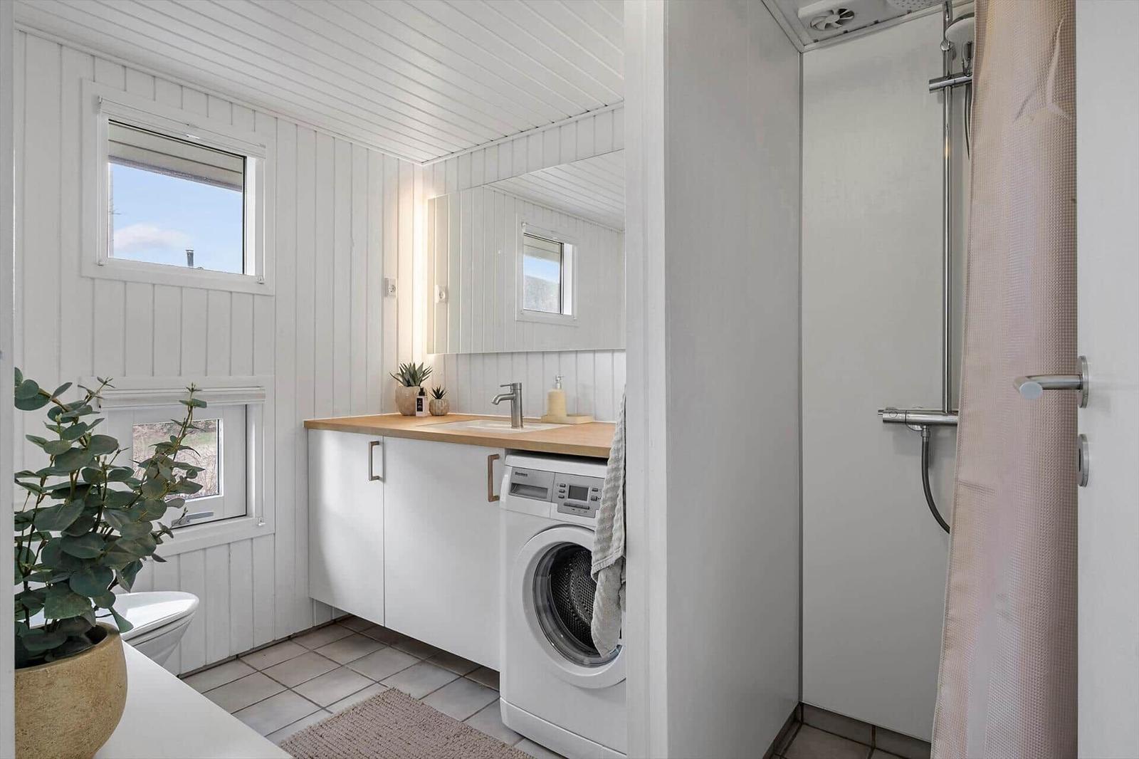 Bathroom with shower, washing machine, and sink with mirror.