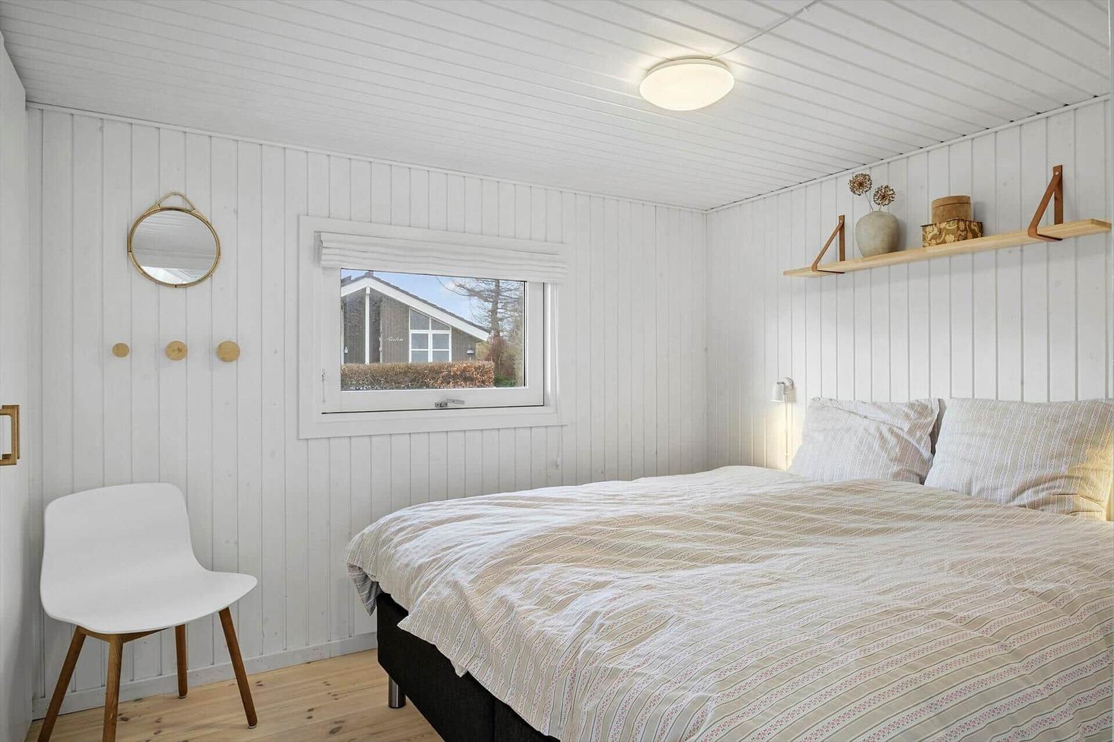 Bedroom with bed, window, and wall shelf. Wooden walls and floor.