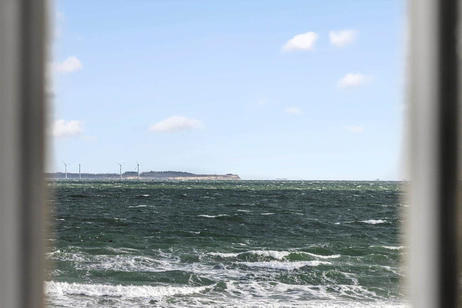 Sea view with wind turbines and rocky horizon through window